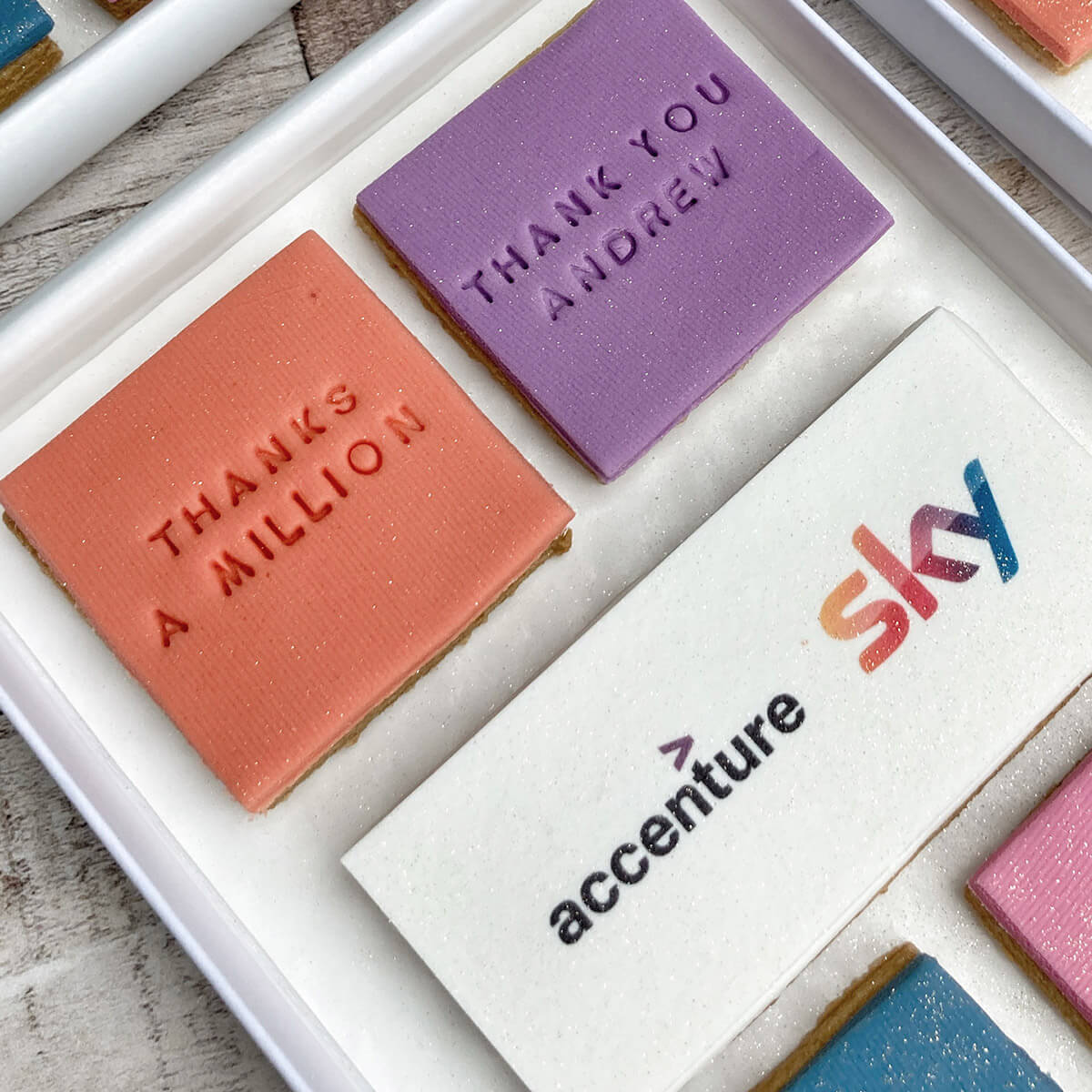 Personalized cookies with messages and logos on a white tray.