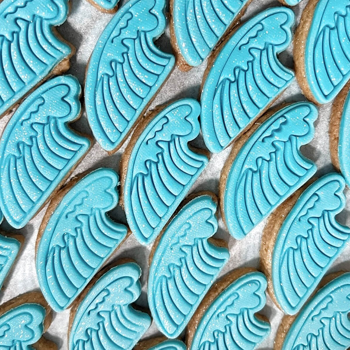 Cookies with blue wave patterns arranged on a baking sheet.