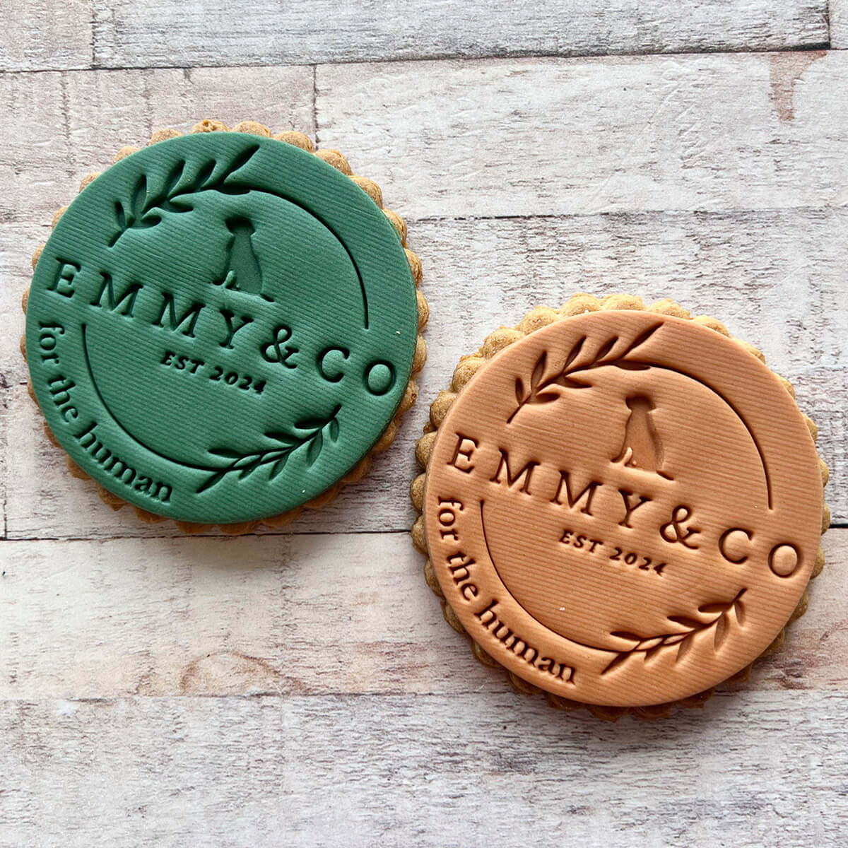 Two round cookies with 'Emmy & Co' branding on a wooden surface