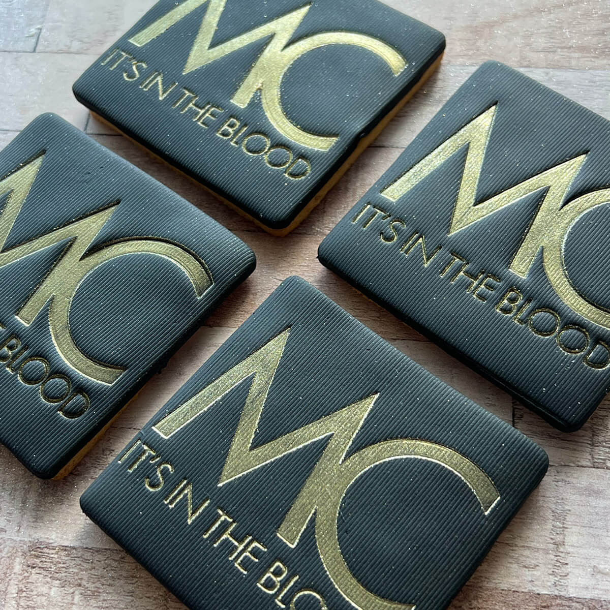 Four dark green biscuits with gold text on a wooden surface