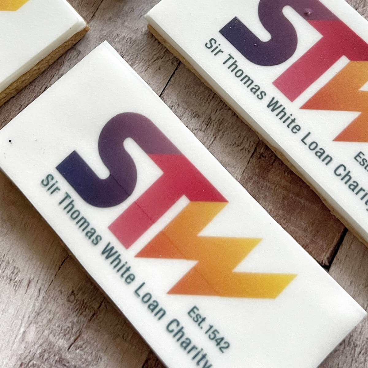 Three rectangular tiles with 'STW' logo and text on a wooden surface