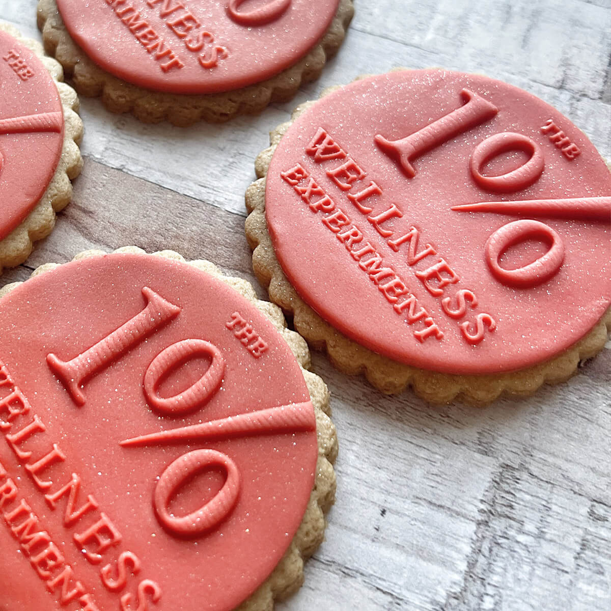 Cookies with '1% Wellness Experiment' stamp on a wooden surface