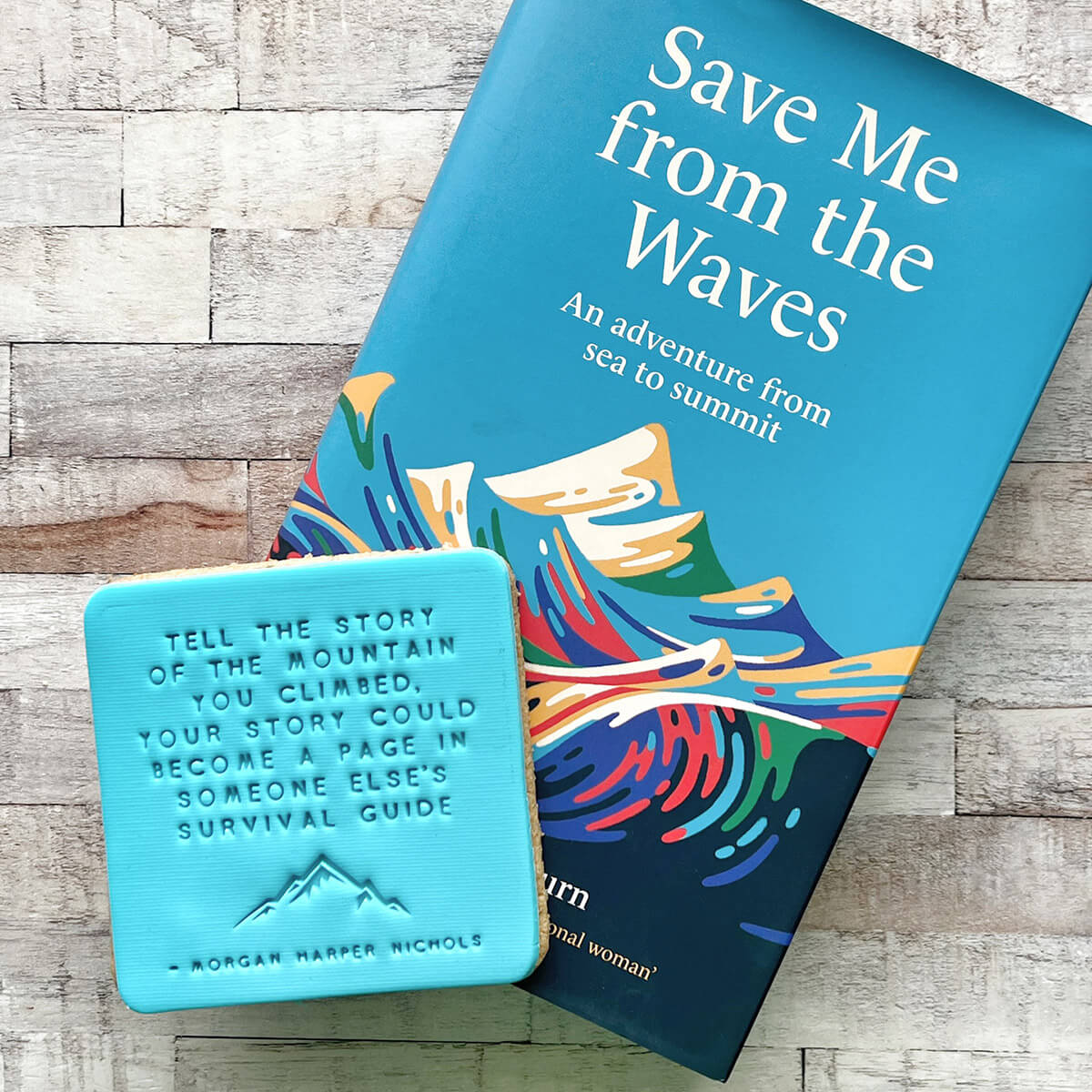 Book titled 'Save Me from the Waves' with a motivational quote biscuit on a wooden surface
