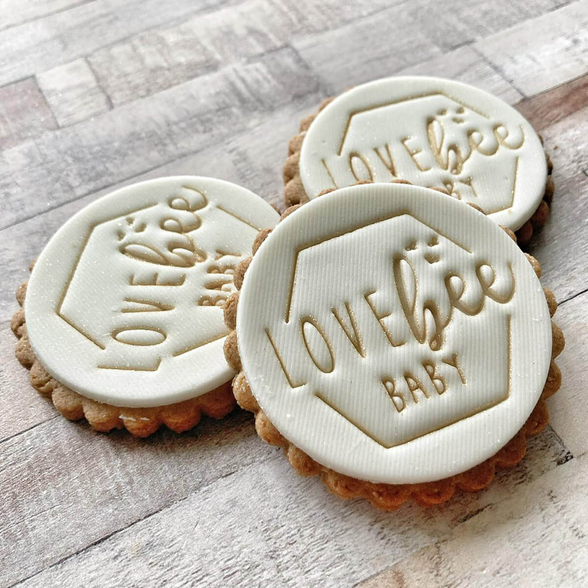 Three cookie cutters with 'LOVE BEE BABY' branding on a wooden surface