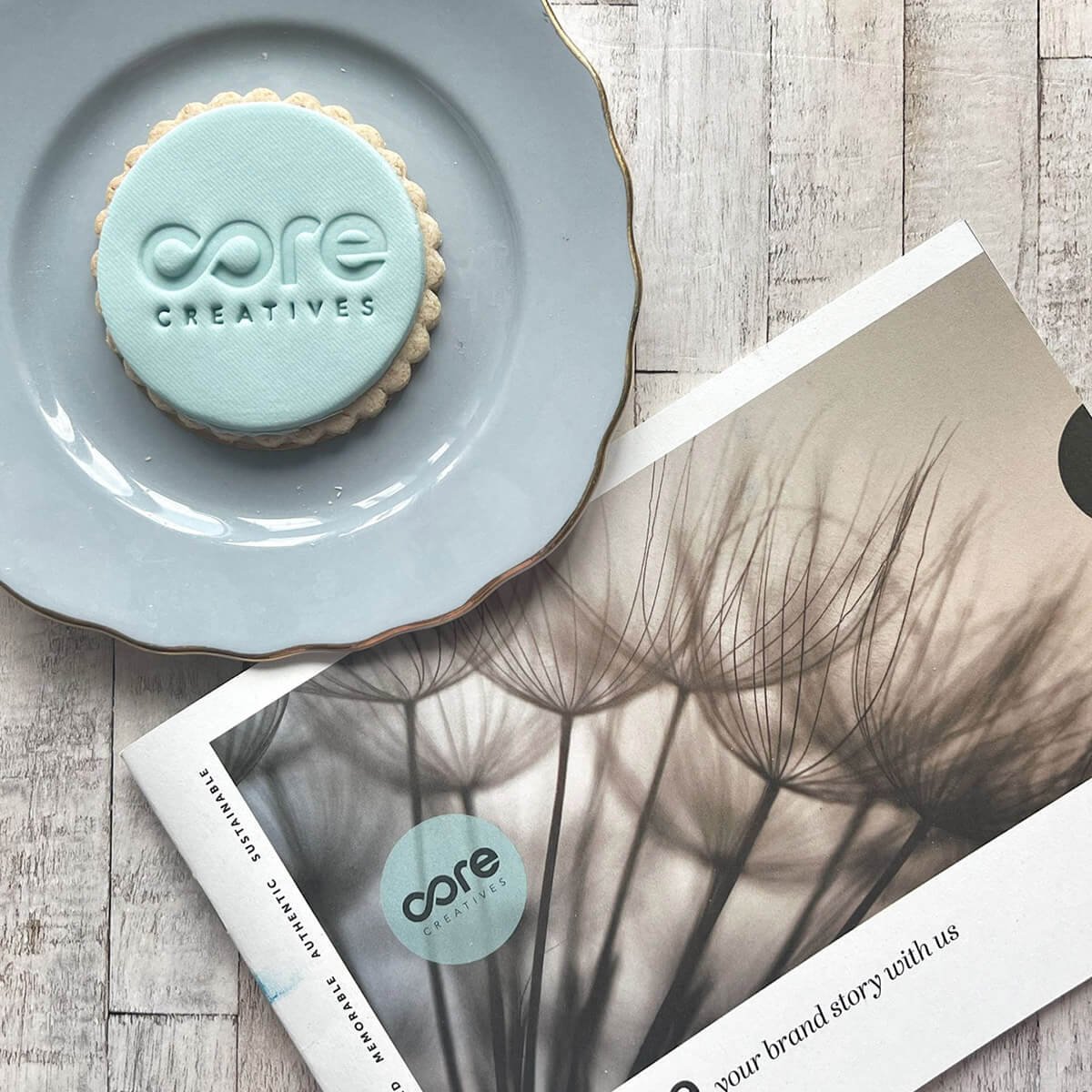 Cookie with 'core creatives' branding on a plate and magazine on a wooden surface