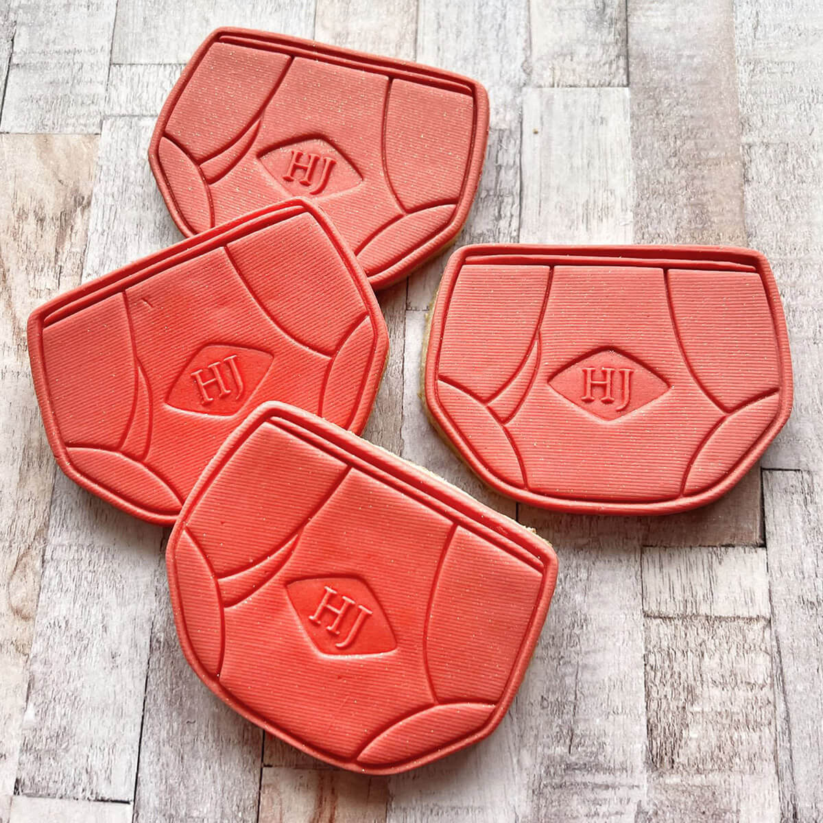 Four red dog mats with 'HJ' logo on a wooden surface