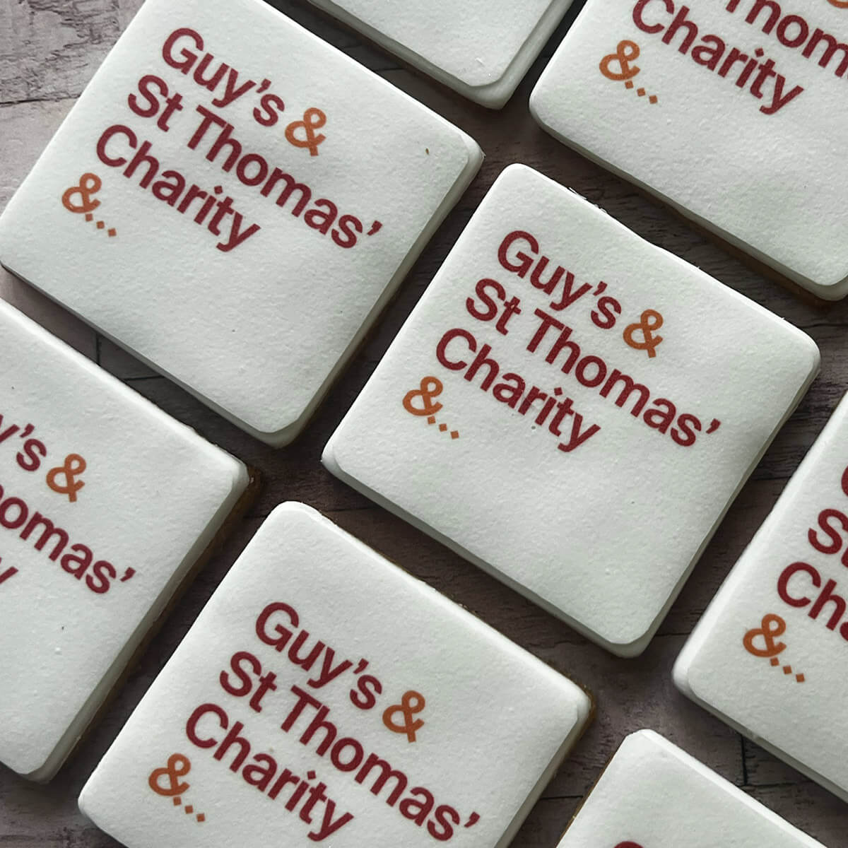 White tiles with 'Guy's & St Thomas' Charity' text on a wooden surface