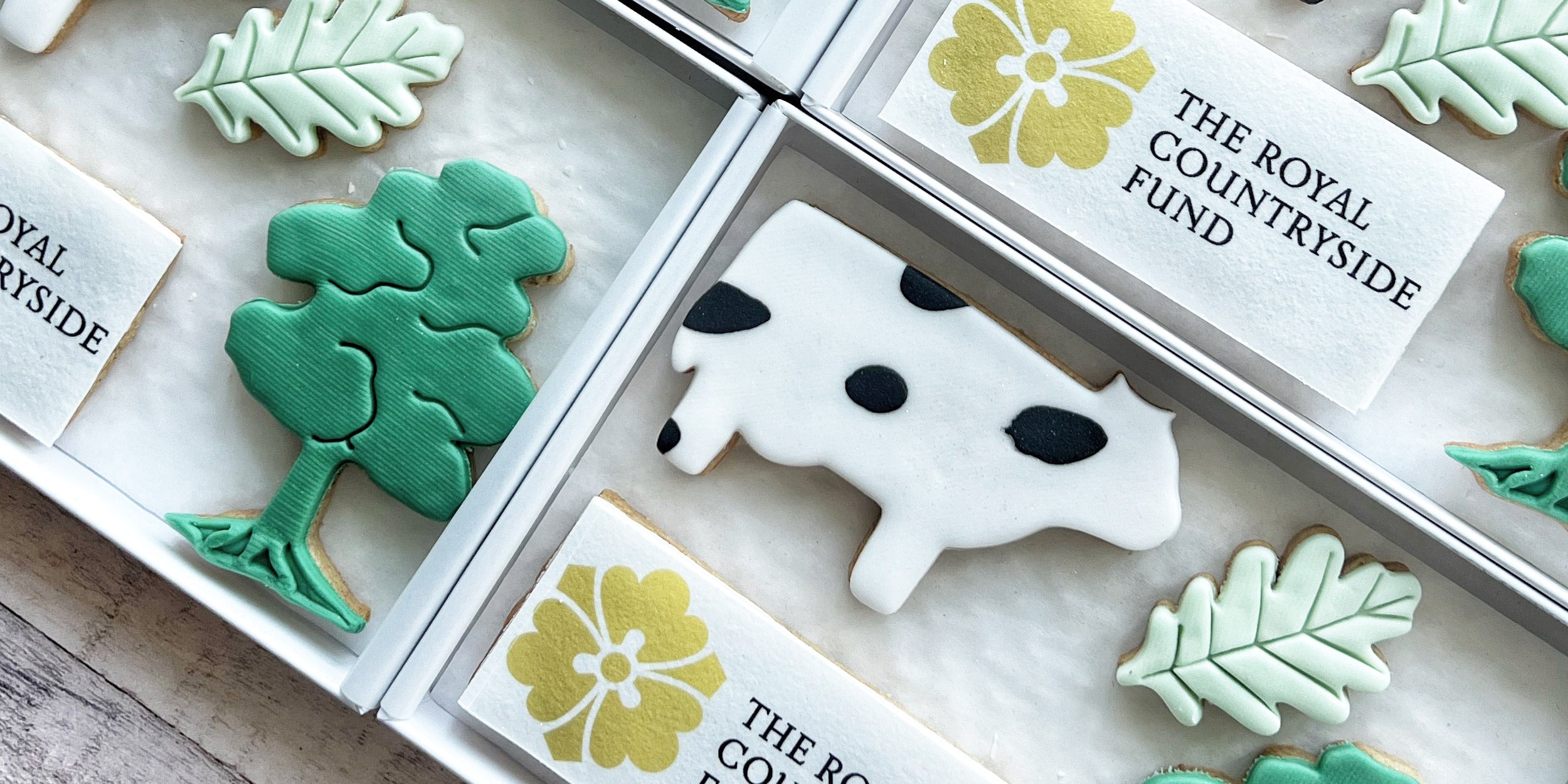 Decorative cookies with animal and nature designs on a branded box.